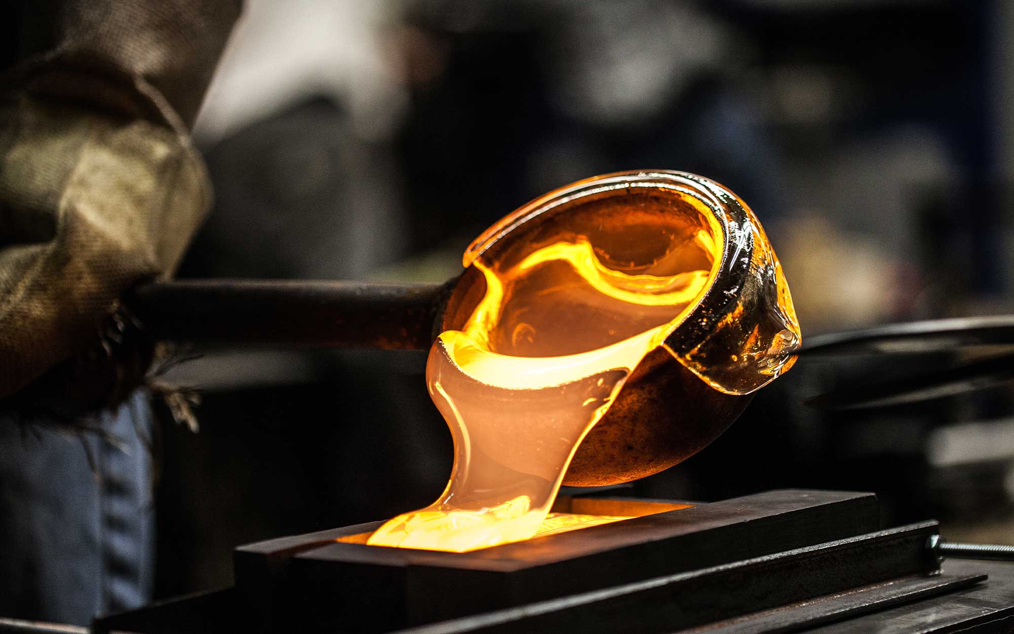 Glassmaker pouring melted sand into glass mold