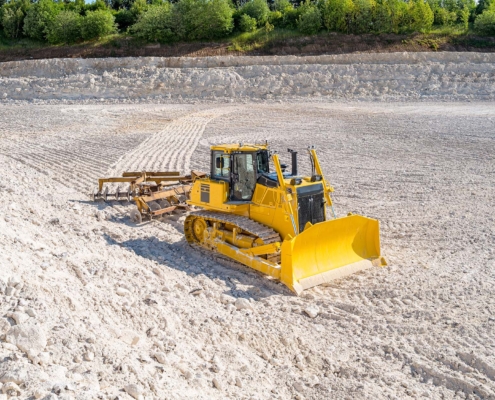 Yellow bulldozer flattening the ground in the limestone quarry_