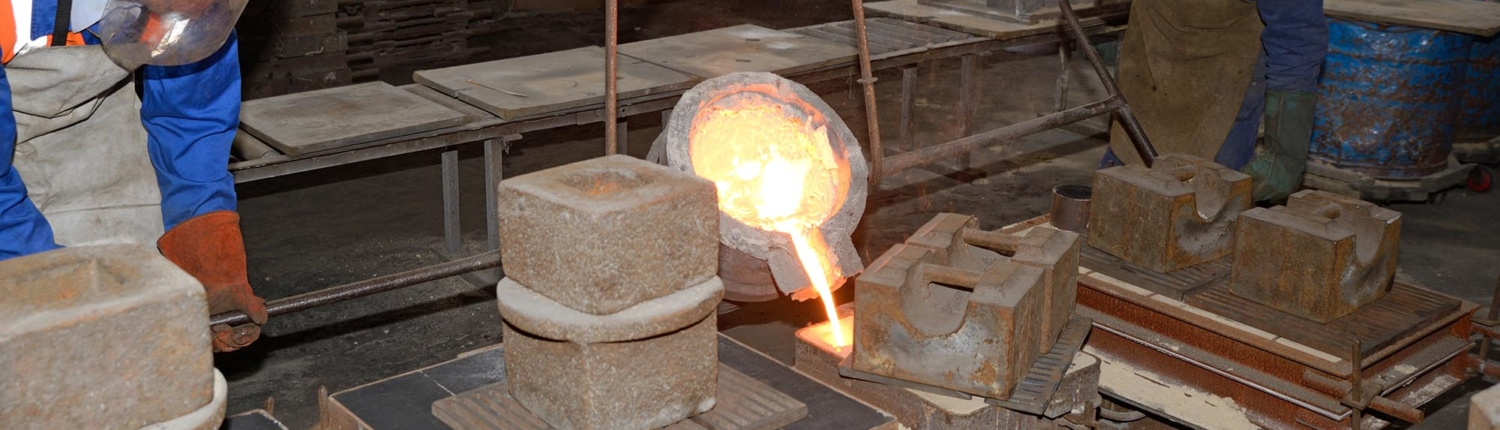 Side view of a founder pouring molten iron in a mould